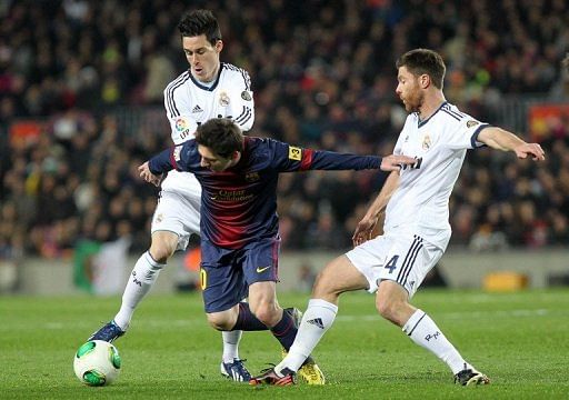 Barcelona's Lionel Messi tries to find a way through Real Madrid's Jose Callejon (L) and Xabi Alonso February 26, 2013